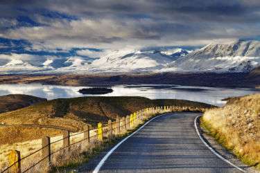 An open road stretching out to the mountains in New Zealand