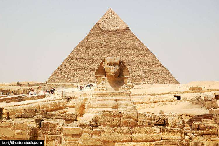 The statue of the sphinx in foreground with the Pyramid of Giza in the background