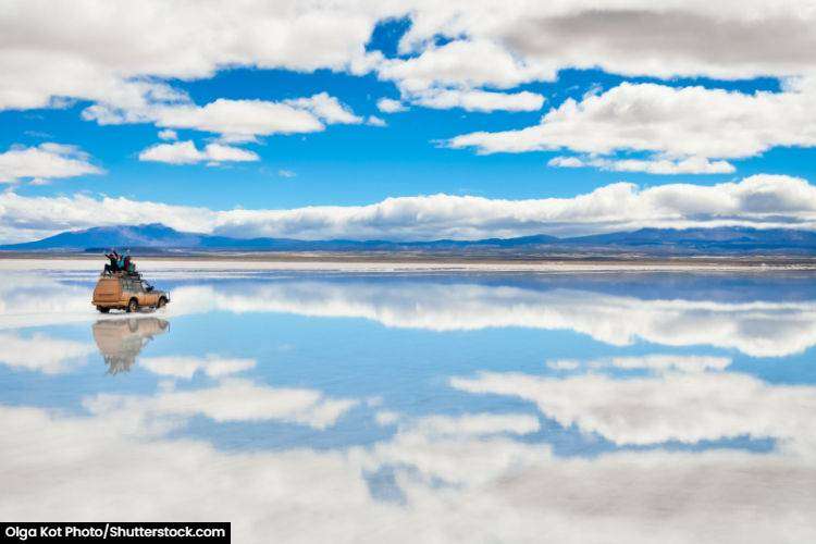 Car driving on the mirror perfect surface of Salar de Uyuni in Bolivia